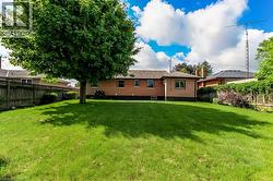 Expansive rear yard featuring a large tree providing shade and a manicured lawn - 