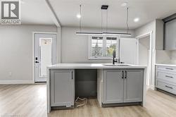 Kitchen island with a white countertop and integrated sink, light gray shaker-style cabinetry, and matte black hardware - 