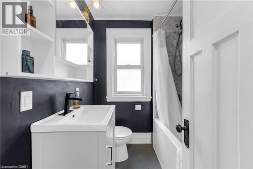 Bathroom featuring a white vanity with integrated sink, black faucet, and a wall-mounted mirrored cabinet - 22 Cope Street, Hamilton, ON 