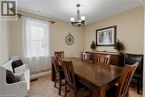 Dining area featuring neutral wall tones, a central chandelier with frosted glass shades, and light-colored carpeting - 2 Mill Street E, York, ON 