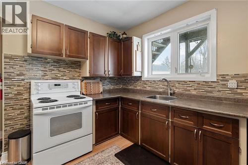 Kitchen featuring wood-finish cabinetry, a mosaic tile backsplash, a stainless steel sink, and a white electric range - 2 Mill Street E, York, ON 