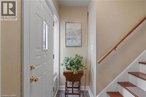 Entryway featuring a paneled door with a rectangular window, brass hardware, and a wood-finish staircase with a natural wood handrail - 2 Mill Street E, York, ON 