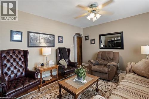 Interior living space featuring light neutral wall paint, a ceiling fan with integrated lighting, wood-finish flooring, a decorative area rug, and an arched entryway - 2 Mill Street E, York, ON 