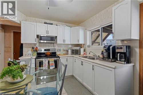 Kitchen featuring white cabinetry, stainless steel appliances, a double basin sink, light-toned countertops, and a window - 2 Mill Street E, York, ON 