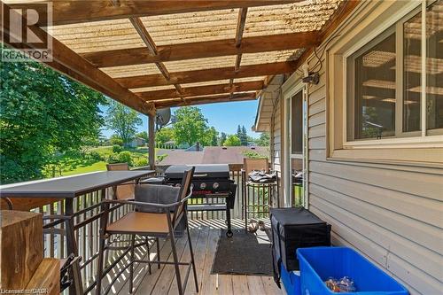 Covered back deck featuring wood-finish decking, a translucent panel roof, and a white vinyl-sided exterior wall - 2 Mill Street E, York, ON 