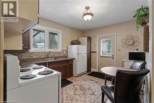 Kitchen featuring wood-finish cabinetry, a mosaic tile backsplash, a stainless steel sink with a gooseneck faucet, and a window with exterior views - 2 Mill Street E, York, ON 