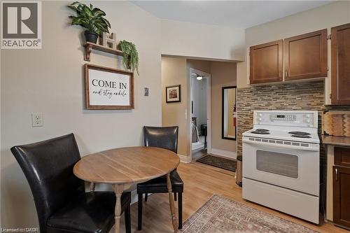 Compact kitchen featuring wood-finish flooring, a white electric range, and a mosaic tile backsplash - 2 Mill Street E, York, ON 