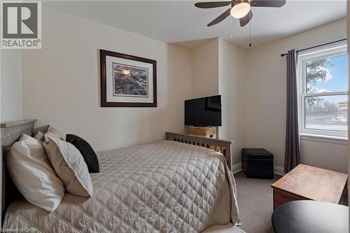 Bedroom featuring a double-hung window with a dark curtain rod, neutral wall paint, and a ceiling fan with integrated lighting - 2 Mill Street E, York, ON 