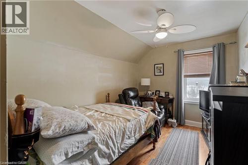 Room featuring wood-finish flooring, a window with horizontal blinds and curtains, a ceiling fan with integrated lighting, and sloped ceiling details - 2 Mill Street E, York, ON 