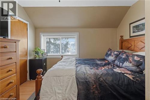Bedroom featuring wood-finish flooring, a window with blinds, and a built-in closet with a wood door - 2 Mill Street E, York, ON 