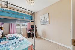 Bedroom featuring neutral wall paint, carpet flooring, a window with a white frame, and a built-in light fixture - 