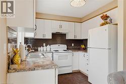 Well-appointed kitchen featuring white cabinetry, a brown subway tile backsplash, and durable laminate countertops - 