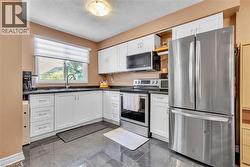 Kitchen featuring white cabinetry, dark speckled countertops, and stainless steel appliances - 