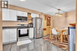 Kitchen featuring white cabinetry, dark speckled countertops, and stainless steel appliances - 