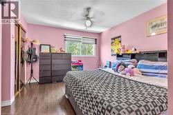 Bedroom featuring wood-finish flooring, a ceiling fan with integrated lighting, a window with horizontal blinds, and a built-in closet with mirrored sliding doors - 