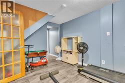 Finished lower level with wood-finish flooring, light blue wall paint, and a wood-paneled ceiling section - 