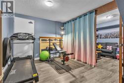 Finished basement space featuring light gray wood-finish flooring, light blue painted walls, and an open doorway to an additional room - 