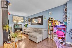 Living area featuring wood-finish flooring, light blue wall paint, and recessed ceiling lighting - 