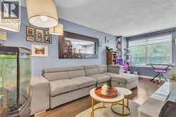 Hardwood-finish flooring extending throughout the living area, featuring a large window with horizontal blinds - 