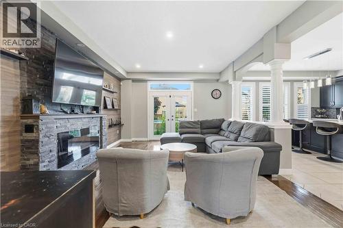 Open-concept living space featuring wood-finish flooring, recessed lighting, and a stone-clad fireplace with a dark wood mantel - 212 Chartwell Circle, Hamilton, ON 