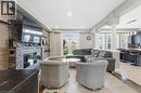 Open-concept living space featuring wood-finish flooring, recessed lighting, and a stone-clad fireplace with a dark wood mantel - 212 Chartwell Circle, Hamilton, ON 