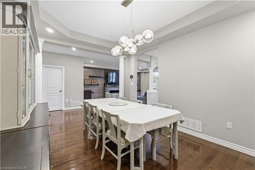 Open-concept dining area featuring wood-finish flooring, a contemporary chandelier, recessed lighting, and tray ceiling detailing - 212 Chartwell Circle, Hamilton, ON 