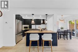 Modern kitchen with black cabinetry, stainless steel appliances, and a central island featuring a light wood countertop - 