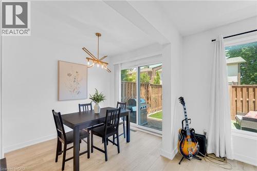 Dining space with wood-finish flooring and a contemporary linear chandelier - 5275 Banting Court, Burlington, ON 