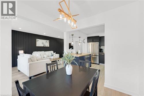 Spacious dining area featuring a dark wood-finish table and an abstract linear chandelier - 5275 Banting Court, Burlington, ON 