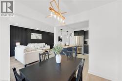 Spacious dining area featuring a dark wood-finish table and an abstract linear chandelier - 