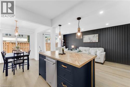 Kitchen island with a herringbone wood-finish countertop, dark blue cabinetry, and integrated dishwasher - 5275 Banting Court, Burlington, ON 