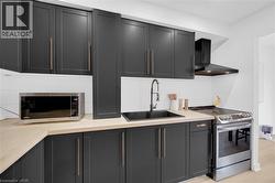 Modern kitchen featuring dark shaker-style cabinetry, light wood-finish countertops, and a white horizontal plank backsplash - 