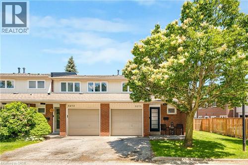 Brick and siding townhome featuring an attached single-car garage, mature front yard tree, and front entry porch with an exterior light fixture - 5275 Banting Court, Burlington, ON 