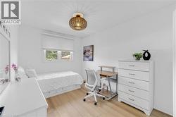 Bright room featuring light wood-finish flooring, white walls, and a window with white blinds - 