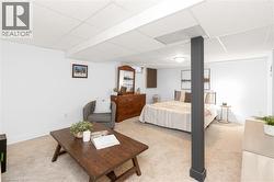 Carpeted room with a drop ceiling, white walls, and a dark support pillar - 