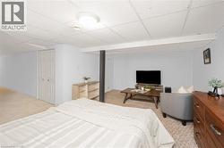 Versatile finished room with neutral carpeting, drop panel ceiling, white bi-fold closet doors, and light blue wall paint - 