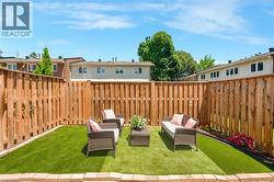 Enclosed backyard featuring a new wood fence and artificial turf - 