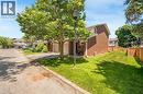Brick exterior residence featuring an attached garage, a private driveway, a fenced yard, and mature trees - 5275 Banting Court, Burlington, ON 