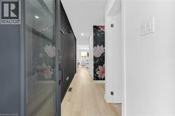 Contemporary hallway featuring light wood-finish flooring, recessed lighting, and a prominent decorative accent wall - 