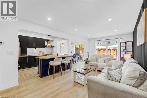 Open-concept living space featuring light wood-finish flooring, recessed lighting, and a modern kitchen - 5275 Banting Court, Burlington, ON 