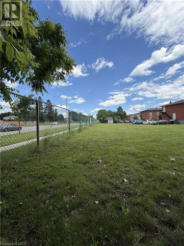 Expansive green lot featuring a chain-link fence border and scattered trees - 26 Carnaby Crescent, Kitchener, ON 