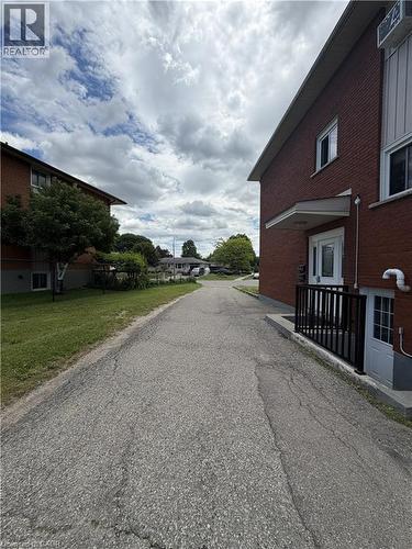 Red brick exterior with white trim, featuring a covered front entry and a dark-framed glass door - 26 Carnaby Crescent, Kitchener, ON 