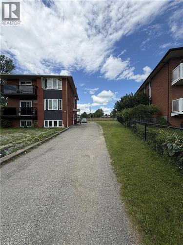 Exterior of a multi-story brick building with white-framed windows and dark trim accents - 26 Carnaby Crescent, Kitchener, ON 