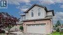 Brick and siding exterior featuring an integrated garage, arched upper windows, and a mature red tree - 59 Highgate Road Unit# 2, Kitchener, ON 