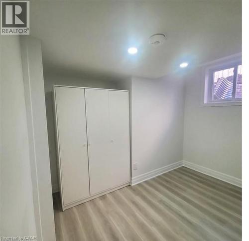 Room featuring light wood-finish flooring, white baseboards, and a white built-in wardrobe with three doors - 59 Highgate Road Unit# 2, Kitchener, ON 