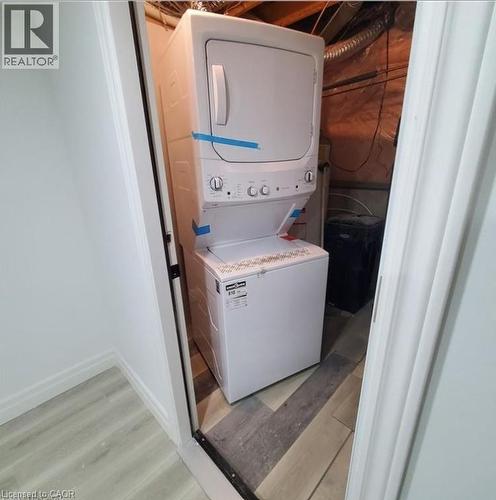 Compact laundry area featuring a stacked washer and dryer unit - 59 Highgate Road Unit# 2, Kitchener, ON 