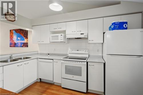 Kitchen featuring white cabinetry, wood-finish flooring, a double basin stainless steel sink, white appliances, and light-toned countertops - 117 E Bristol Road E Unit# 64, Mississauga, ON 