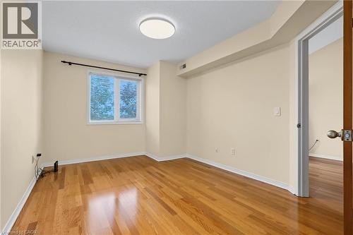 Hardwood flooring throughout featuring a window with white trim, a flush mount ceiling light fixture, and a solid wood interior door - 117 E Bristol Road E Unit# 64, Mississauga, ON 