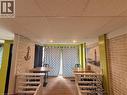 Recessed lighting illuminates the space, featuring wood-finish flooring, drop ceiling panels, and light-colored brick-style wall accents - 486 James Street N, Hamilton, ON 