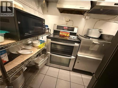 Functional kitchen space featuring a stainless steel double oven range, stainless steel vent hoods, and industrial-style wire shelving - 486 James Street N, Hamilton, ON 